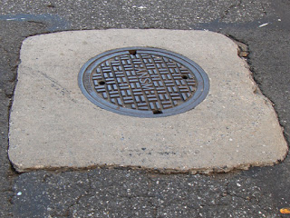 Uneven gradient transition from road to concrete manhole collar