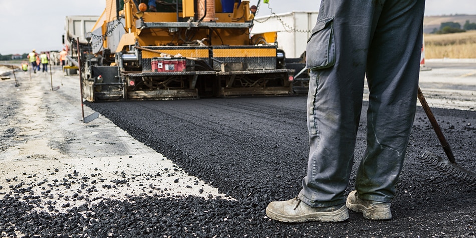 man standing on road being paved