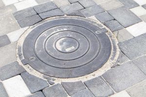 gray manhole lid on cobblestone street